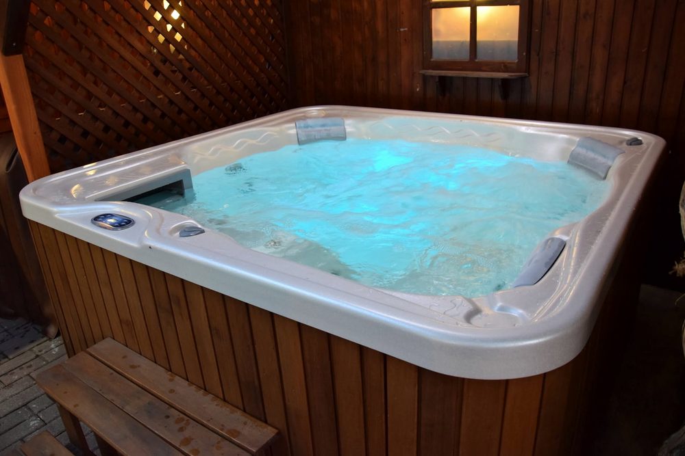 A kerti jakuzzi közelről, felkavart vízzel és fejtámaszokkal