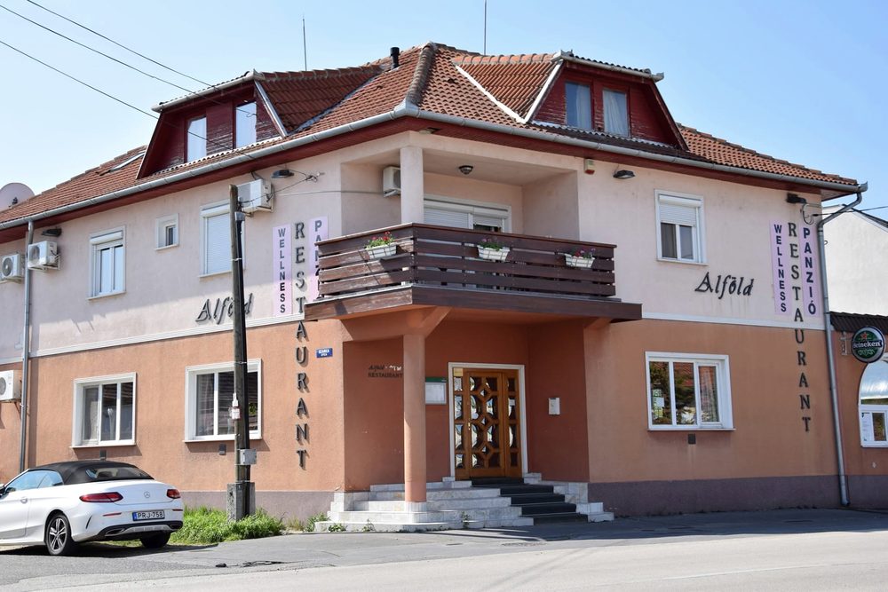 Az Alföld Panzió és Étterem sarokháza a Szolnoki úton, a homlokzaton Wellness, Restaurant és Panzió feliratokkal